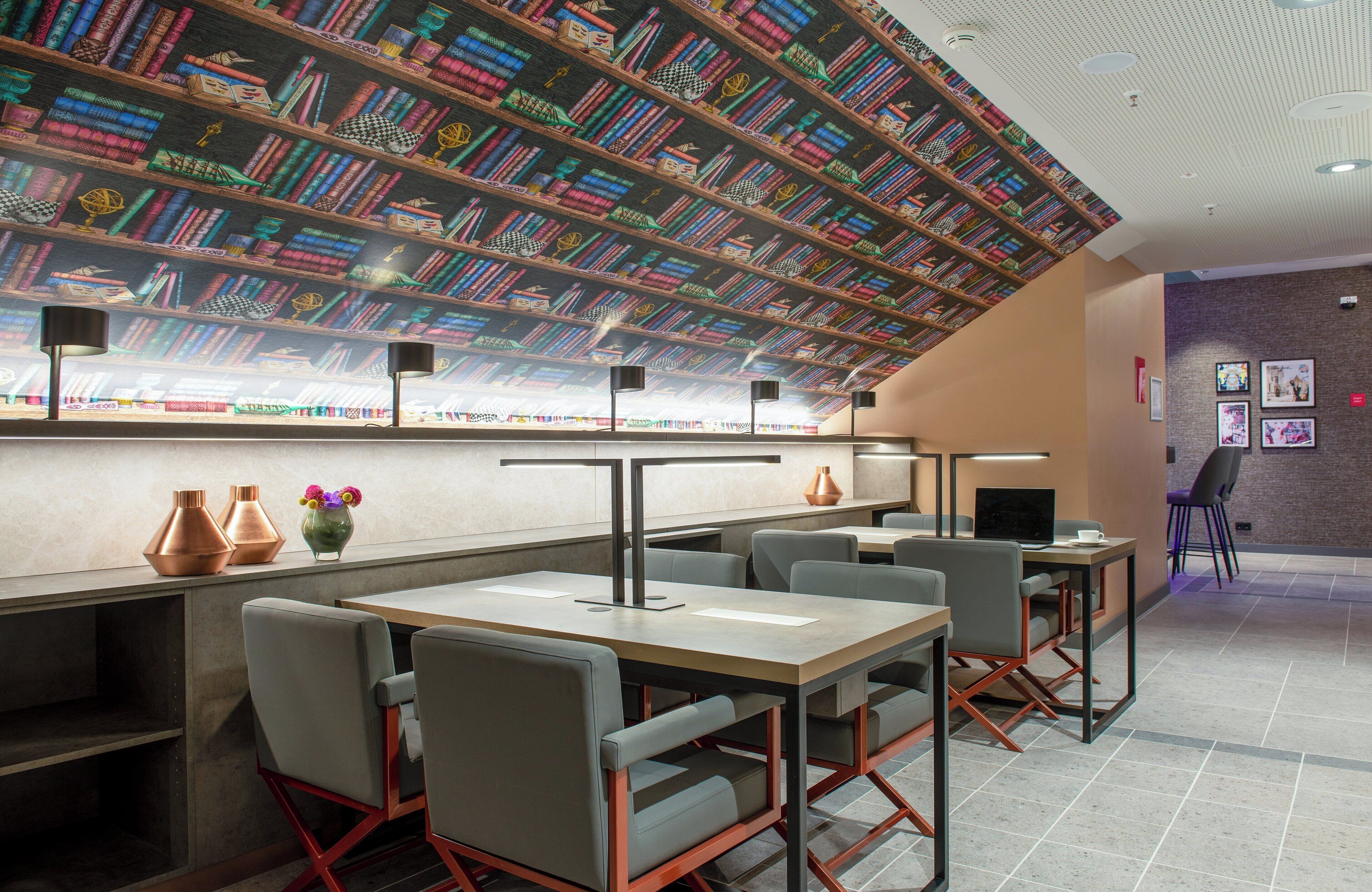 A modern library with bookshelves, tables, and chairs.