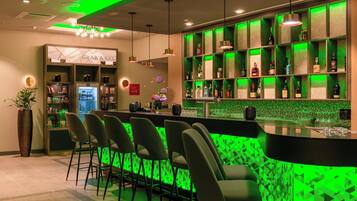 A bar area with green lighting, a 'Grab & Go' section, and a variety of bottles on shelves.