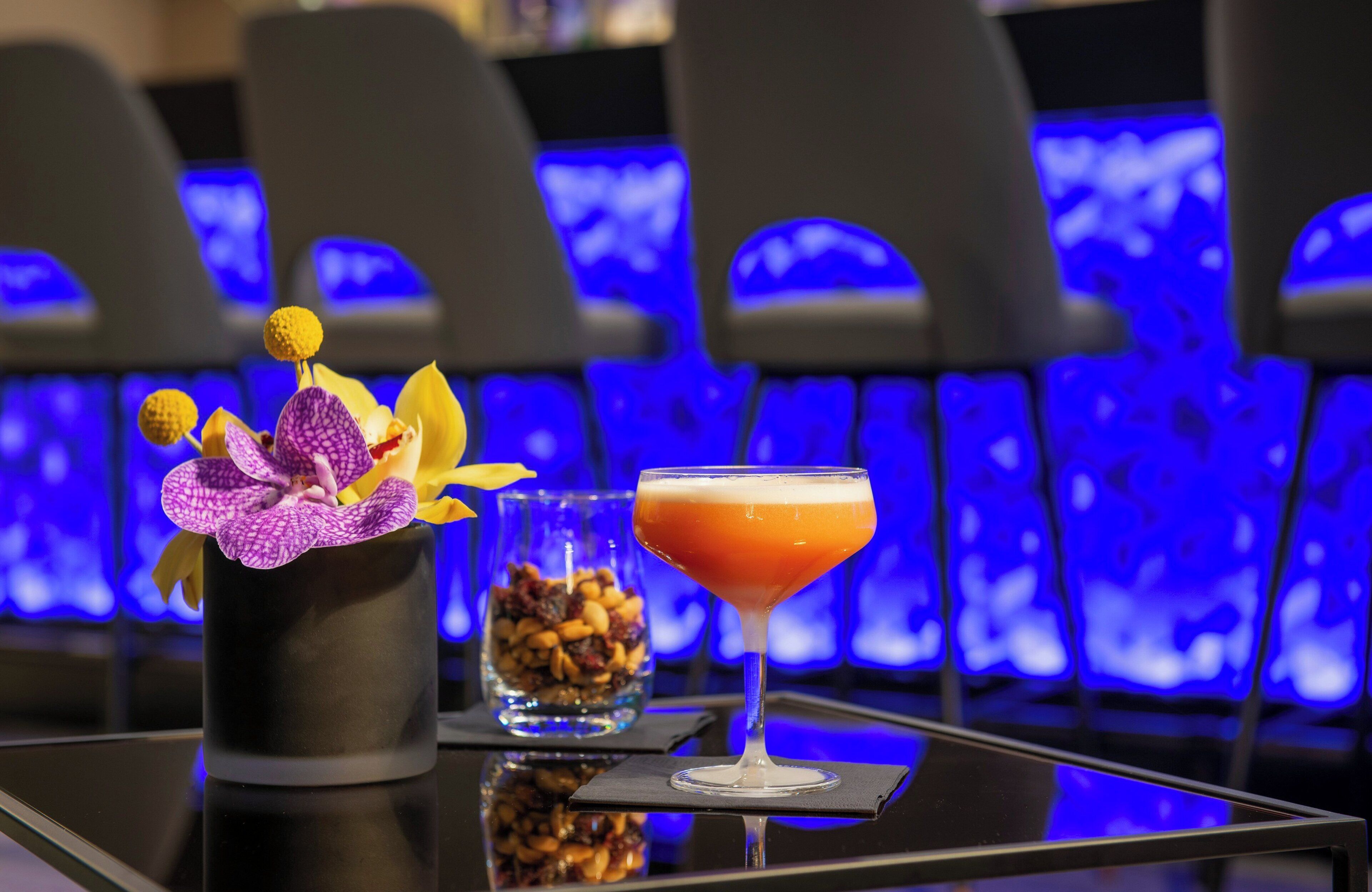Una zona de bar con una copa de cóctel y un florero sobre una superficie reflectante.