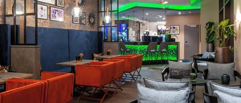 A modern restaurant with orange and grey seating, a green accent wall, and a counter area.