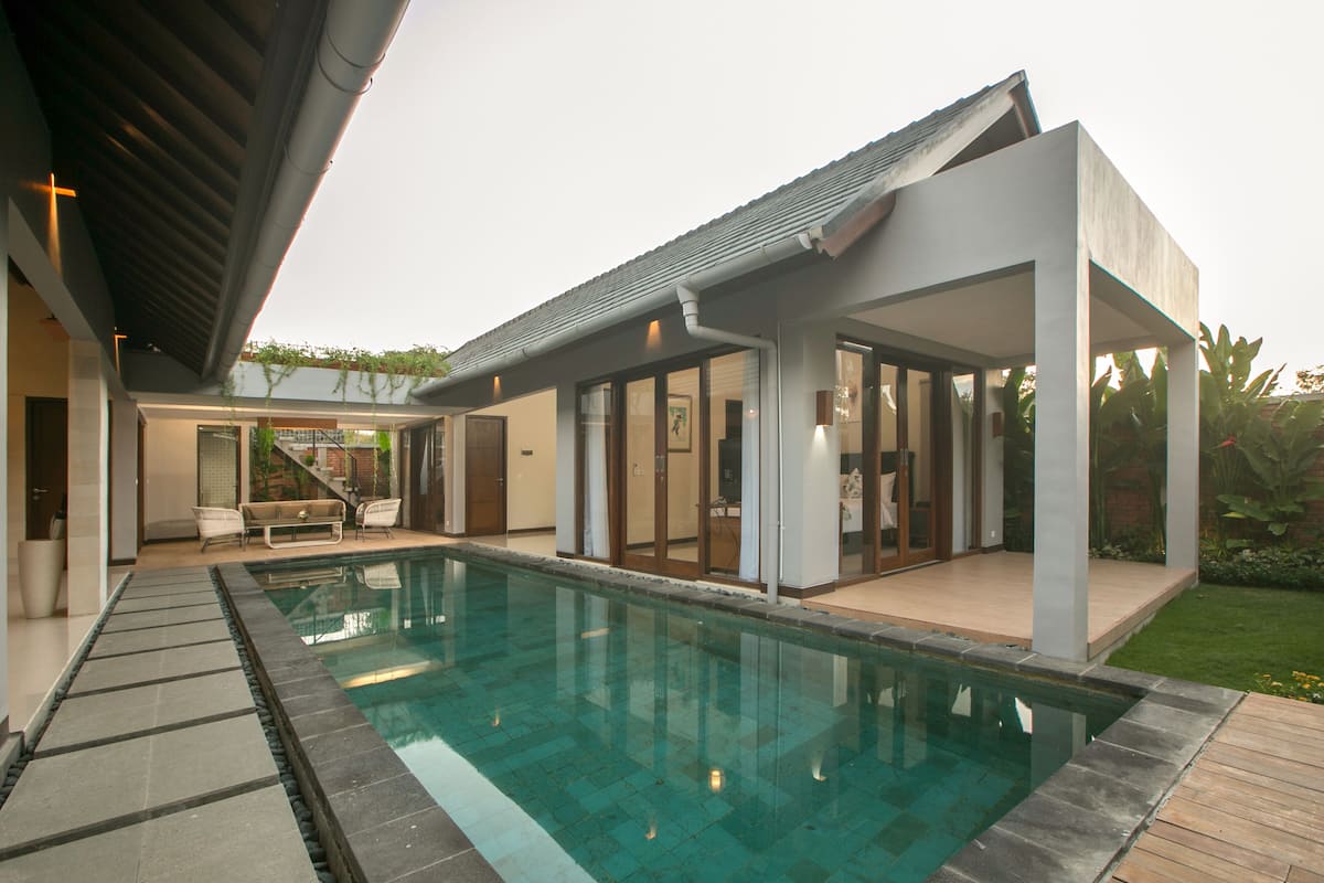 A modern house with a swimming pool, a covered patio, and a view of a staircase leading to a second floor.