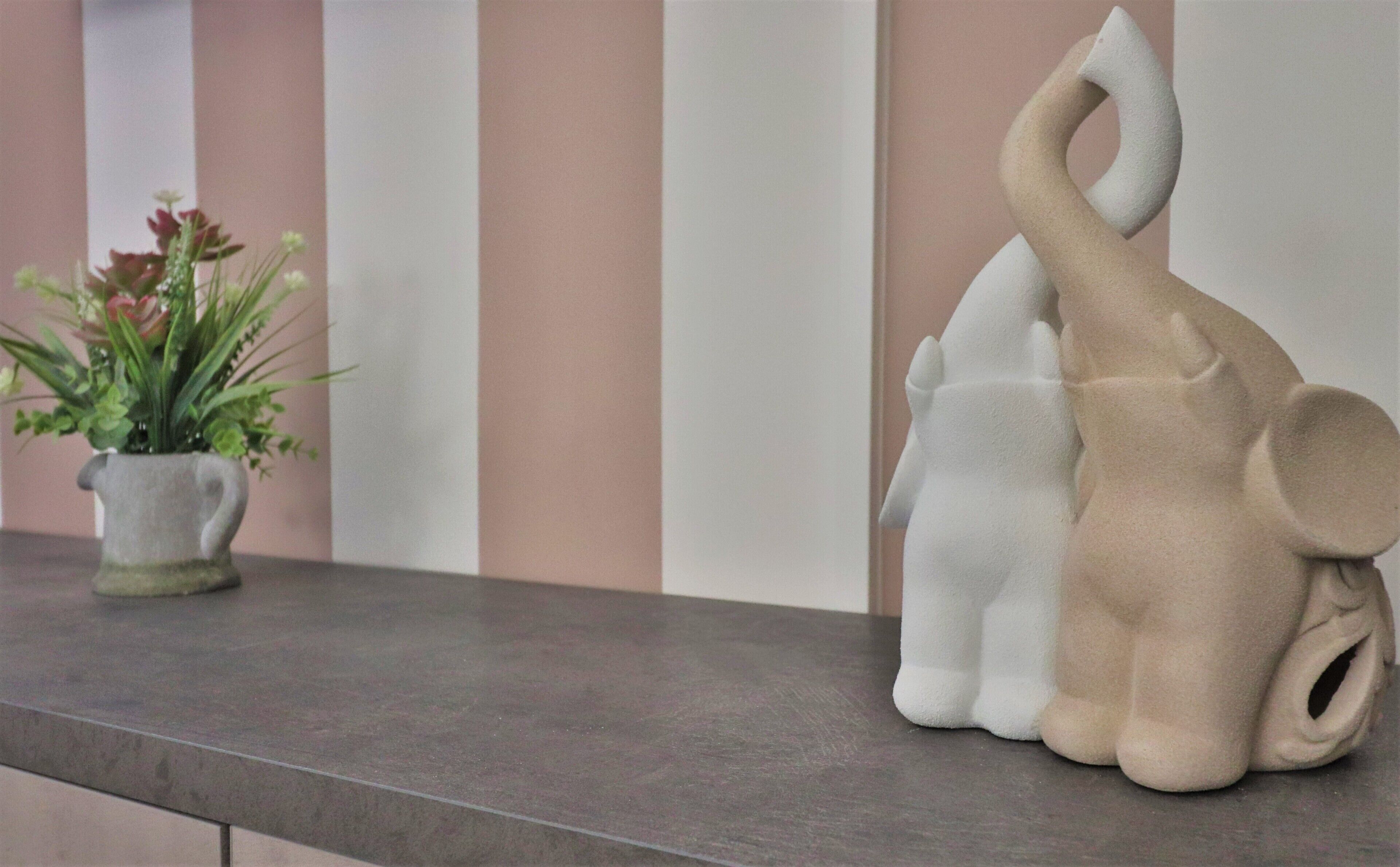A shelf with two ceramic elephant sculptures and a small potted plant.
