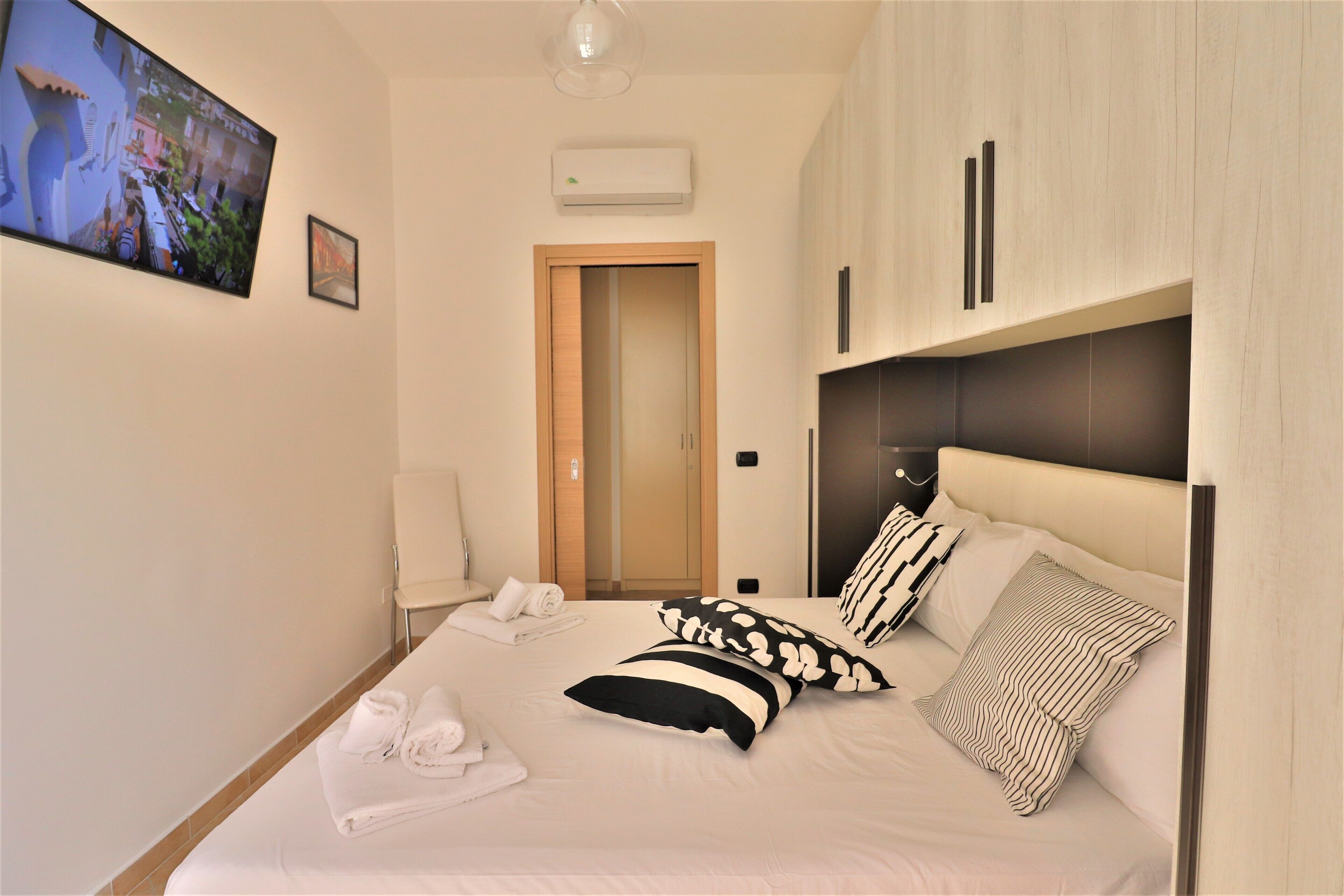 A hotel room with a bed, a TV, a door, and a wardrobe.