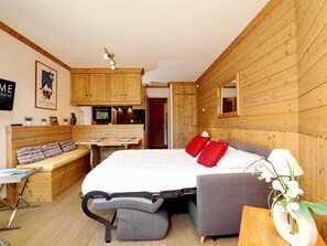 A compact room with a bed, a desk, and a kitchenette. - Courchevel 1850 Ski-in/ski-out studio with parking and wifi (Courchevel 1850)