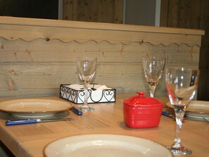 A wooden table with plates, glasses, a red pot, and a heart-shaped box. - Courchevel 1850 Ski-in/ski-out studio with parking and wifi (Courchevel 1850)