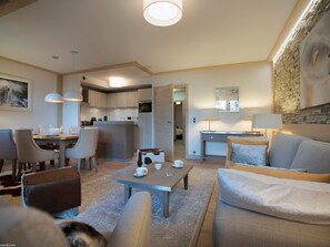 A modern living room with a dining area, a kitchen, and a bedroom.