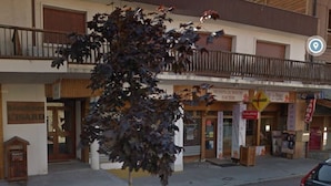 Un edificio con escaparate, un letrero que dice 'Le Bar' y un cartel de 'Prensa' sobre la entrada.