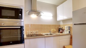 Una cocina moderna con horno empotrado, microondas, lavaplatos y cafetera.