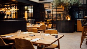 A restaurant with wooden tables, chairs, and a bar area.
