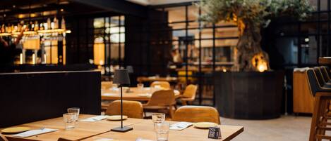 A restaurant with wooden tables, chairs, and a bar area.