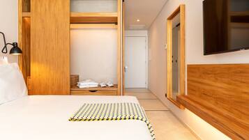 A modern bedroom with a bed, a wooden wardrobe, a TV, and a bedside lamp.