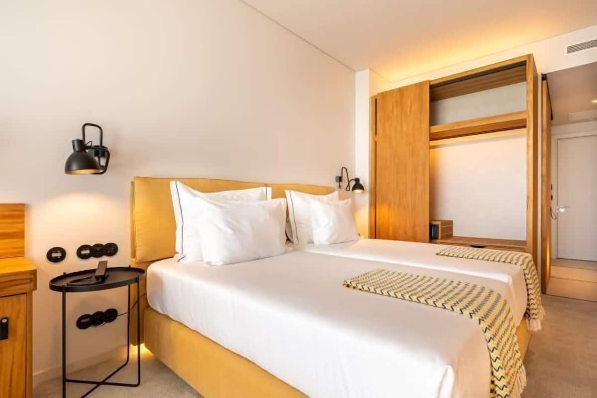 A hotel room with a bed, bedside tables, a lamp, and a wardrobe.