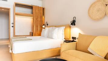 A modern bedroom with a bed, a sofa, a bedside table, and a wall-mounted lamp.