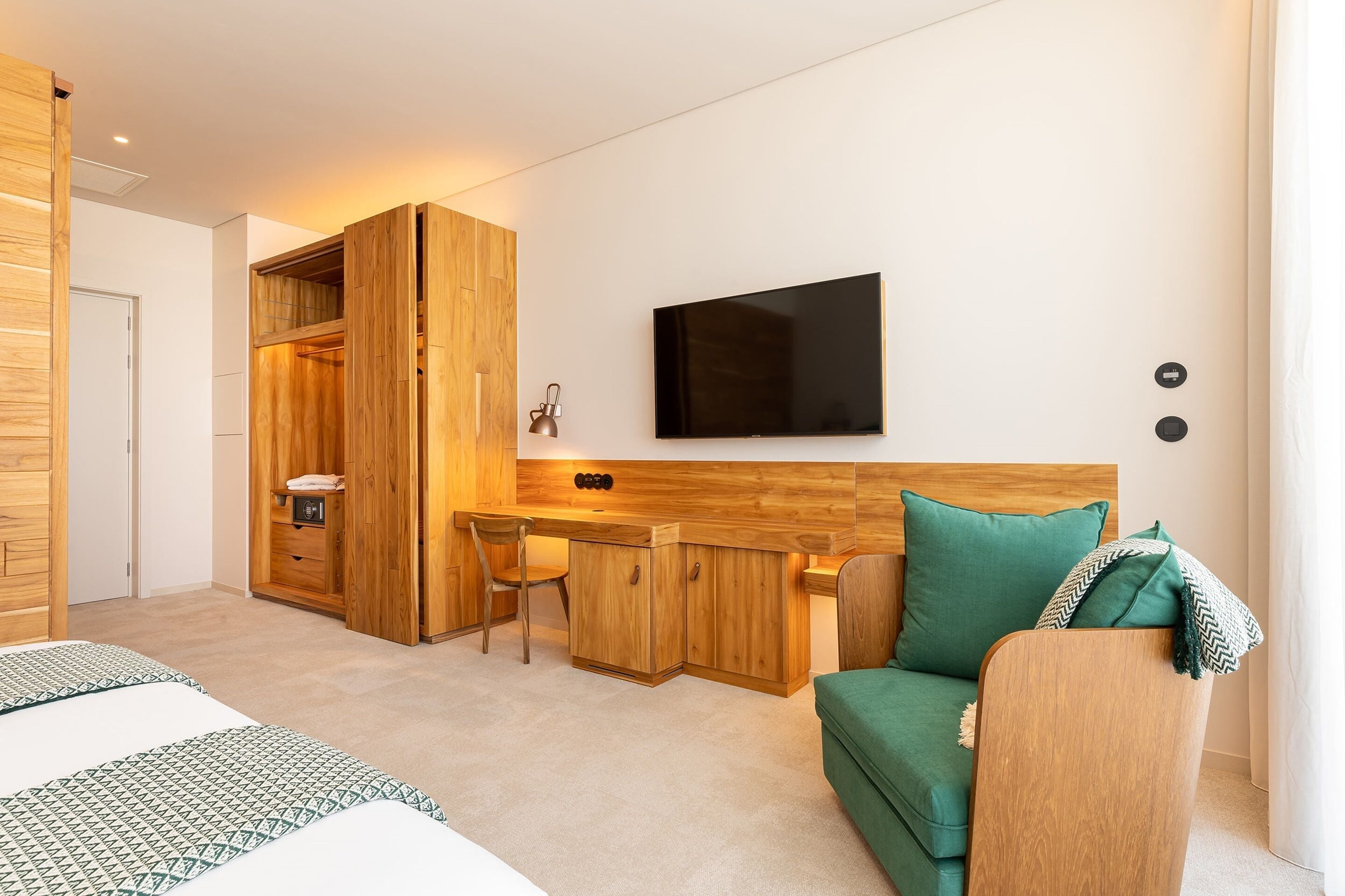 Quarto de hotel moderno com uma escrivaninha de madeira, uma cama e um sofá verde.