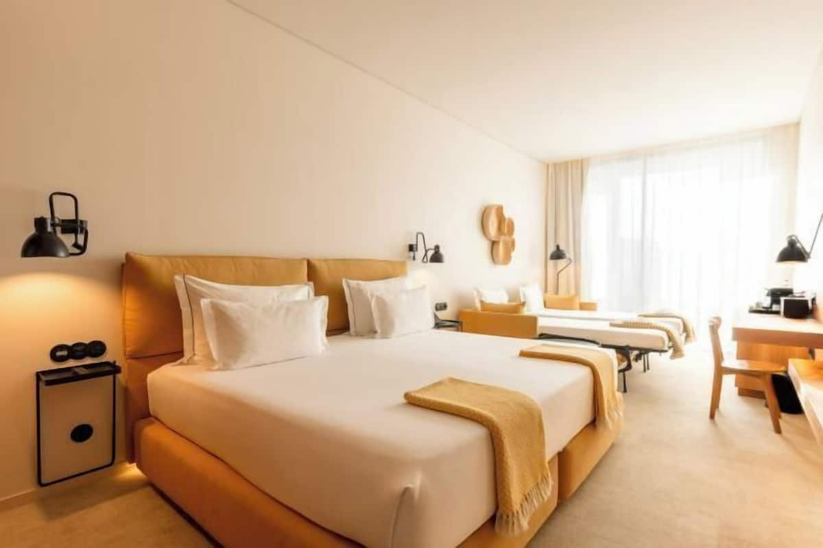 A hotel room with a large bed, bedside tables, a desk, and a chair.