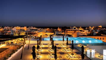 Una piscina techada, una piscina al aire libre, sombrillas