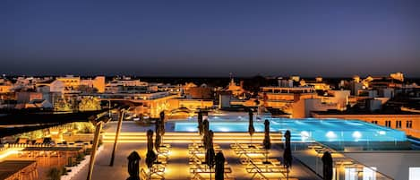 Una piscina cubierta, una piscina al aire libre, sombrillas, tumbonas