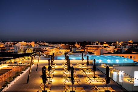 Una piscina techada, una piscina al aire libre, sombrillas