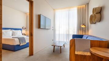 Een moderne hotelkamer met een bed, een bank en een kleine tafel.
