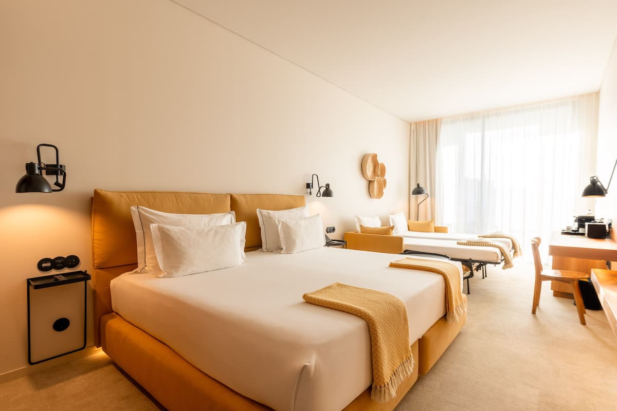 A hotel room with a large bed, bedside tables, a desk, and a chair.