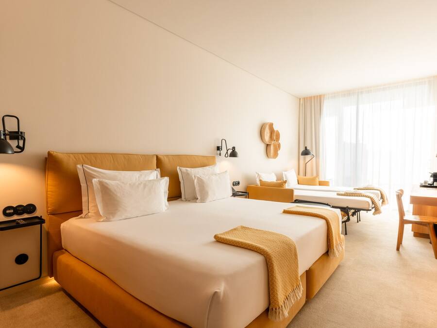 A hotel room with a large bed, bedside tables, a desk, and a chair.