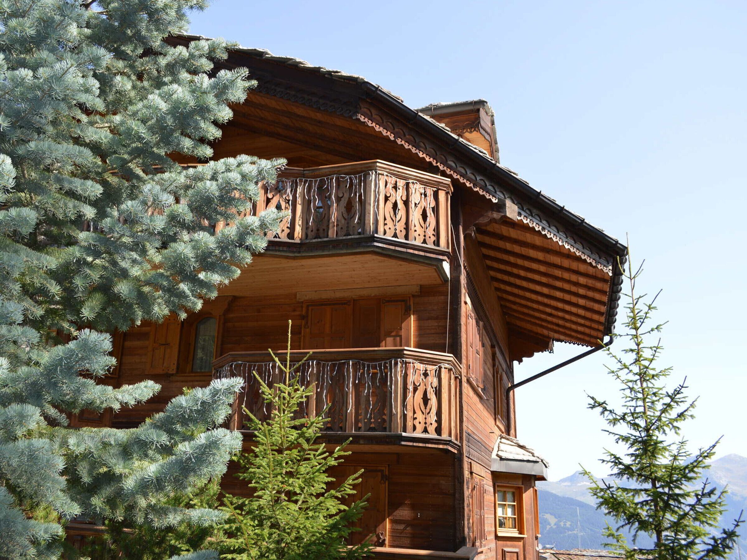 Eine Holzhütte mit Balkon, umgeben von immergrünen Bäumen.