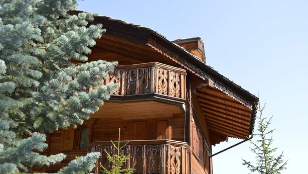 A wooden chalet with a balcony, surrounded by evergreen trees. - Elegant duplex in Courchevel 1850 with fireplace and private parking (Courchevel 1850)