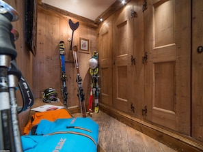 A room with wooden walls, a bed with an orange blanket, and skis leaning against the wall.