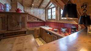 A wooden kitchen with a tiled backsplash, a wooden table, and a hanging light fixture. - Elegant duplex in Courchevel 1850 with fireplace and private parking (Courchevel 1850)