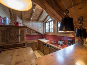 Une cuisine en bois avec un mur recouvert de carreaux, une table en bois et un luminaire suspendu.