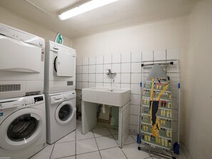 Une buanderie équipée d’un lave-linge, d’un sèche-linge et d’une table à repasser.