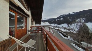 Ein Holzbalkon mit Blick auf ein verschneites Tal und Berge.