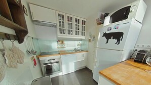 Eine kleine Küche mit weißen Schränken, einer Mikrowelle und einem Kühlschrank.