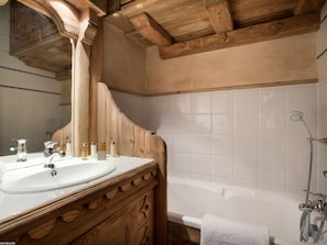 A wooden bathroom vanity with a sink and mirror, a bathtub, and a shower.