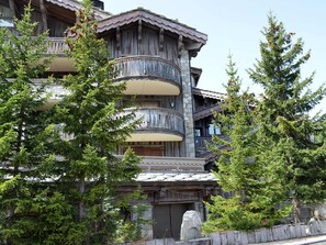 A multi-story building with balconies, surrounded by trees. - Courchevel 1850 Duplex Mezzanine 6 Pax, Ski-in/Ski-out, Parking (Courchevel 1850)