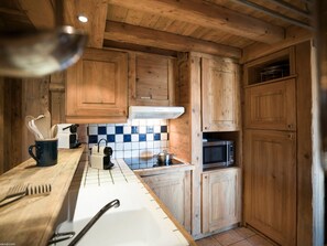 A kitchen with wooden cabinets, a microwave, a kettle, and a coffee maker. - Courchevel 1850 Duplex Mezzanine 6 Pax, Ski-in/Ski-out, Parking (Courchevel 1850)