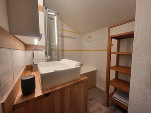 A modern bathroom with a white sink, wooden vanity, and a glass shower enclosure. - Renovated family apartment in Courchevel 1550, 3 rooms (Courchevel 1550)