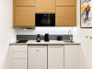 Une cuisine moderne avec des meubles en bois, un four noir et un évier en acier inoxydable.