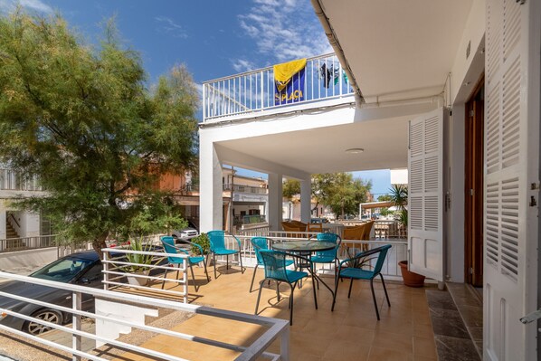 A terrace with outdoor seating, a balcony with a flag, and a car parked nearby.