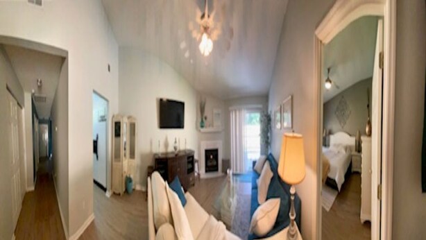 A spacious living area with a sofa, a lamp, and a fireplace. There is a hallway leading to another room.