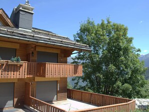 A two-story building with a balcony, a garage, and a view of a mountain. - Charming apartment in Courchevel with large terrace (Courchevel 1550)