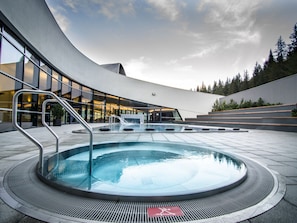 A modern building with a curved exterior and a central pool area with a wheelchair-accessible path.
