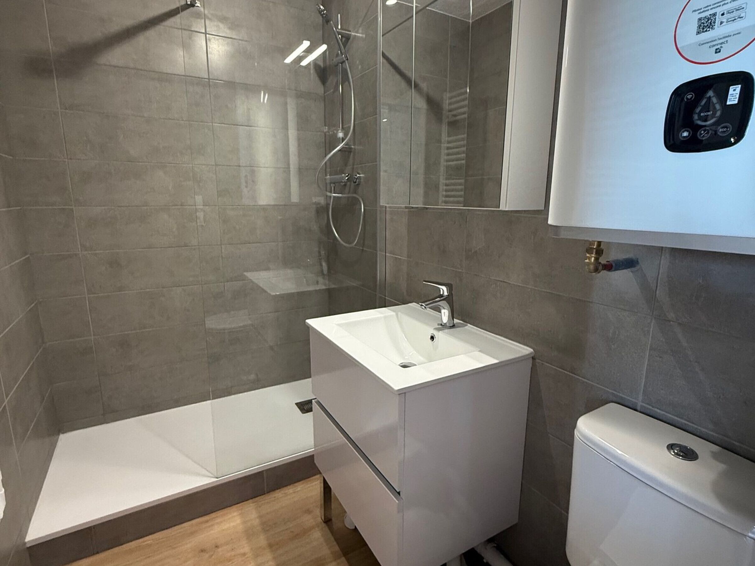 A modern bathroom with a shower, sink, and toilet.