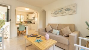 Ein modernes Wohnzimmer mit einer Couch, einem Couchtisch und einer Küche im Hintergrund.