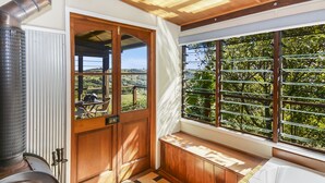 Una habitación acogedora con un ventanal grande, un banco de madera y un estufa de leña.