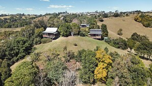 Un paisaje montañoso con dos casas modernas rodeadas de abundante vegetación.
