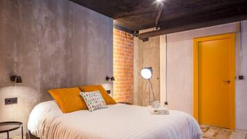 Un dormitori amb un llit, una làmpada, una paret de maó i una porta.