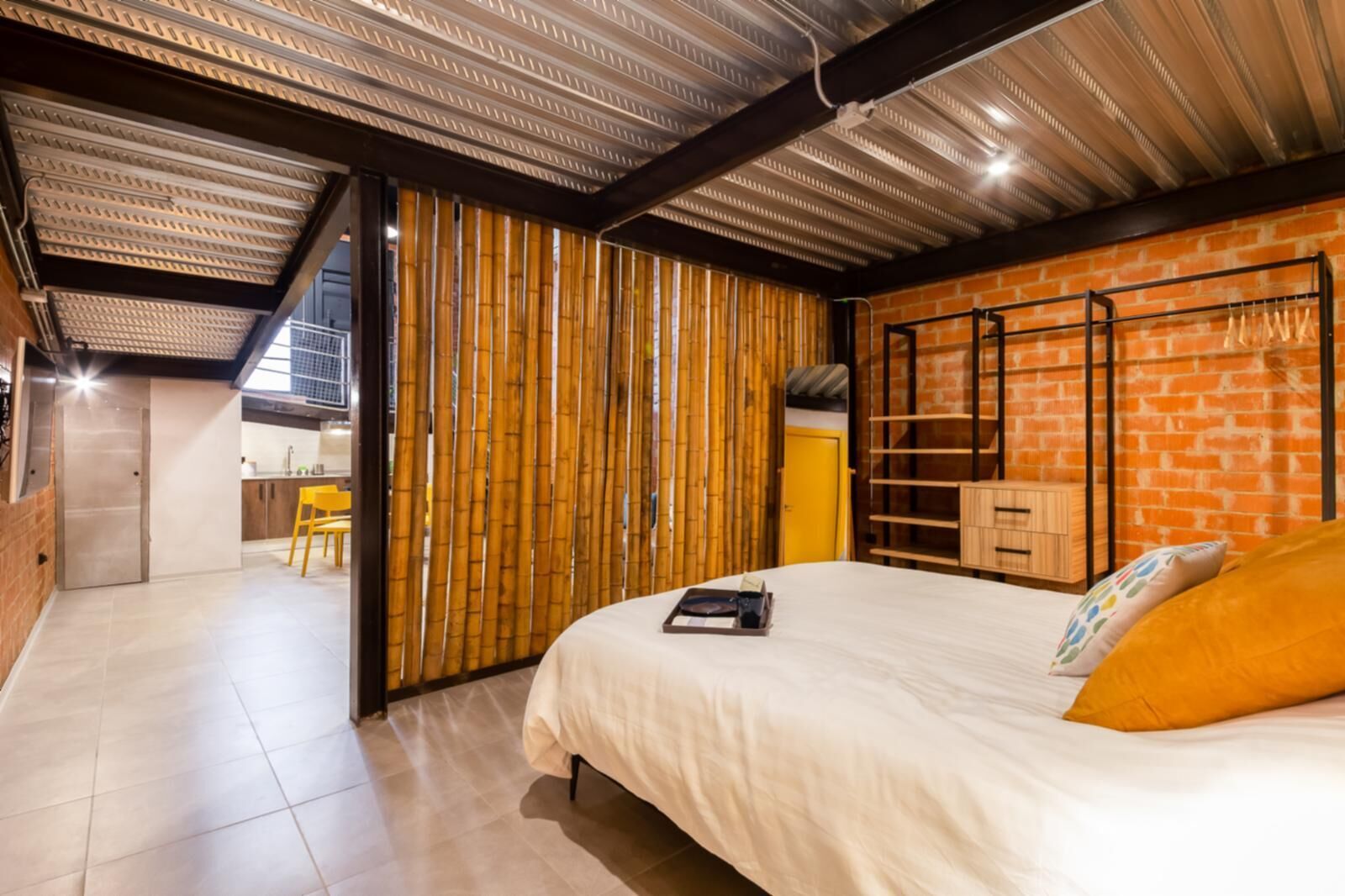 Ein modernes Schlafzimmer mit Bett, einer Bambusabtrennung und einer Ziegelwand.