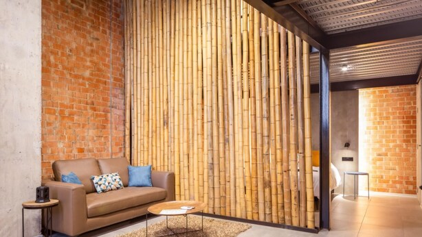 A modern living room with a brick wall, a bamboo wall divider, a brown leather sofa, a round coffee table, and a small side table. - Art Loft 05 'The Mechanic' in Valencia (València)