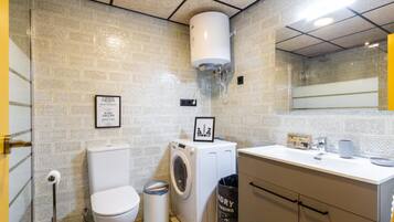 Un baño pequeño con inodoro, lavadora y lavamanos.